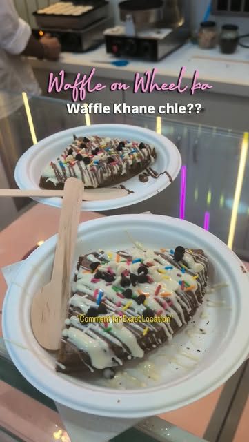 Two chocolate-dipped waffles with sprinkles served on paper plates